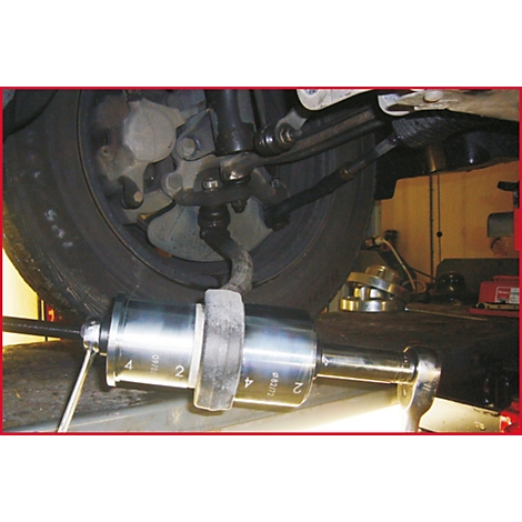 Nahaufnahme eines Werkzeugs, das an einem Autoreifen montiert ist. Die Reifen sind schwarz und stehen auf einer Hebebühne. Die Werkzeuge sind aus Metall.